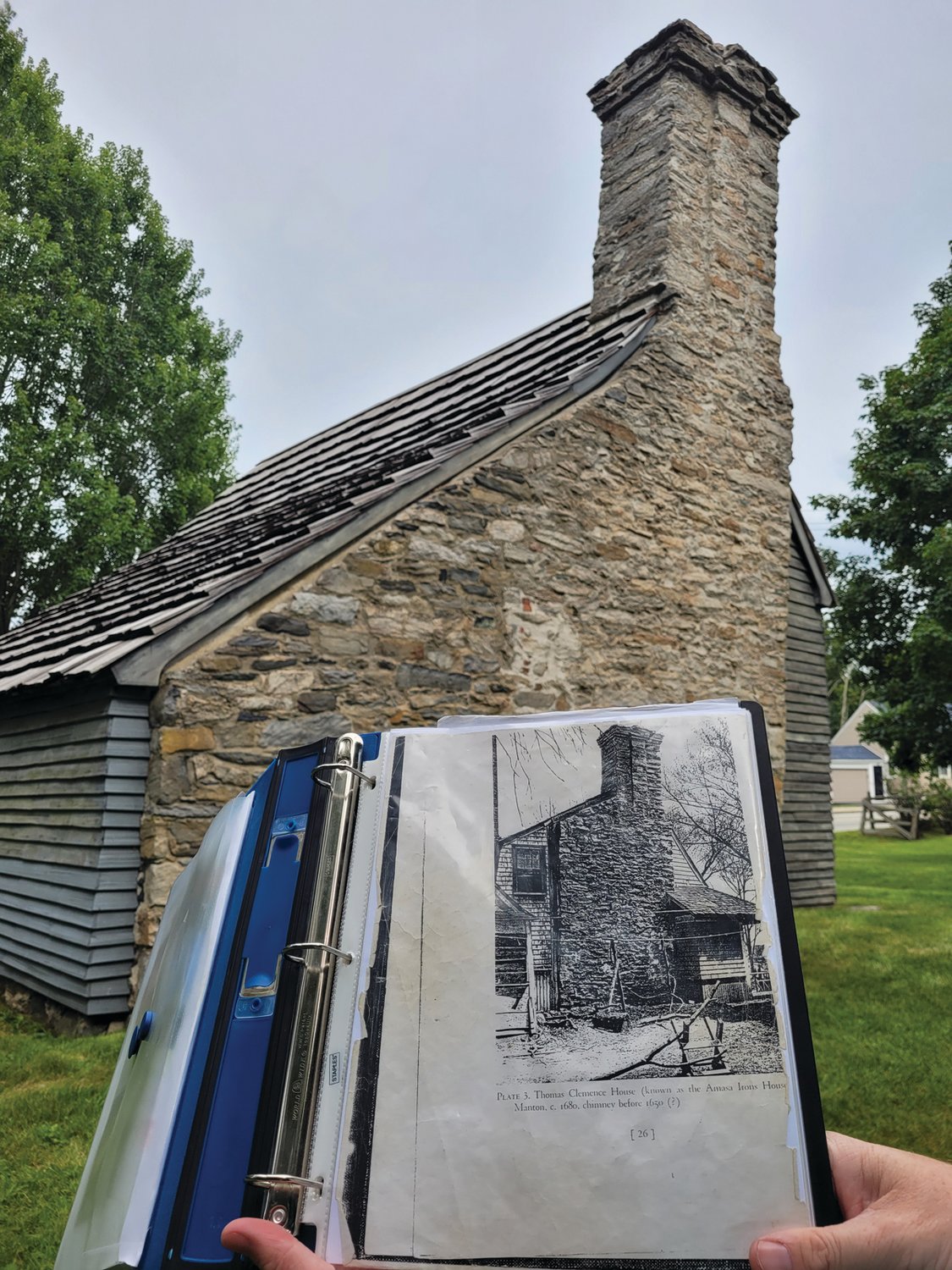 STONE-ENDER: The Clemence-Irons House is a rare surviving ‘stone-ender,’ a type of architecture used by New England’s earliest European settlers. Most houses of this type burned during King Phillip’s War. Caretaker Dan Santos holds a historical photo of the structure, showing some early additions to the home, which have since been removed.